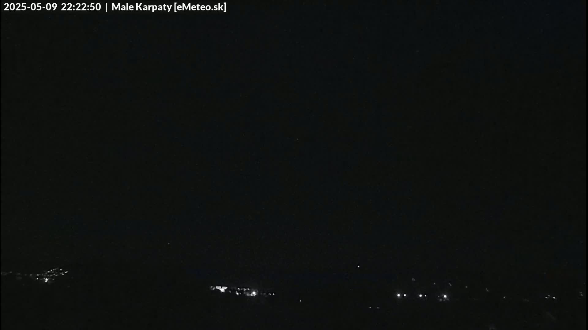 A nighttime long shot shows a dark sky over a distant line of faint lights.