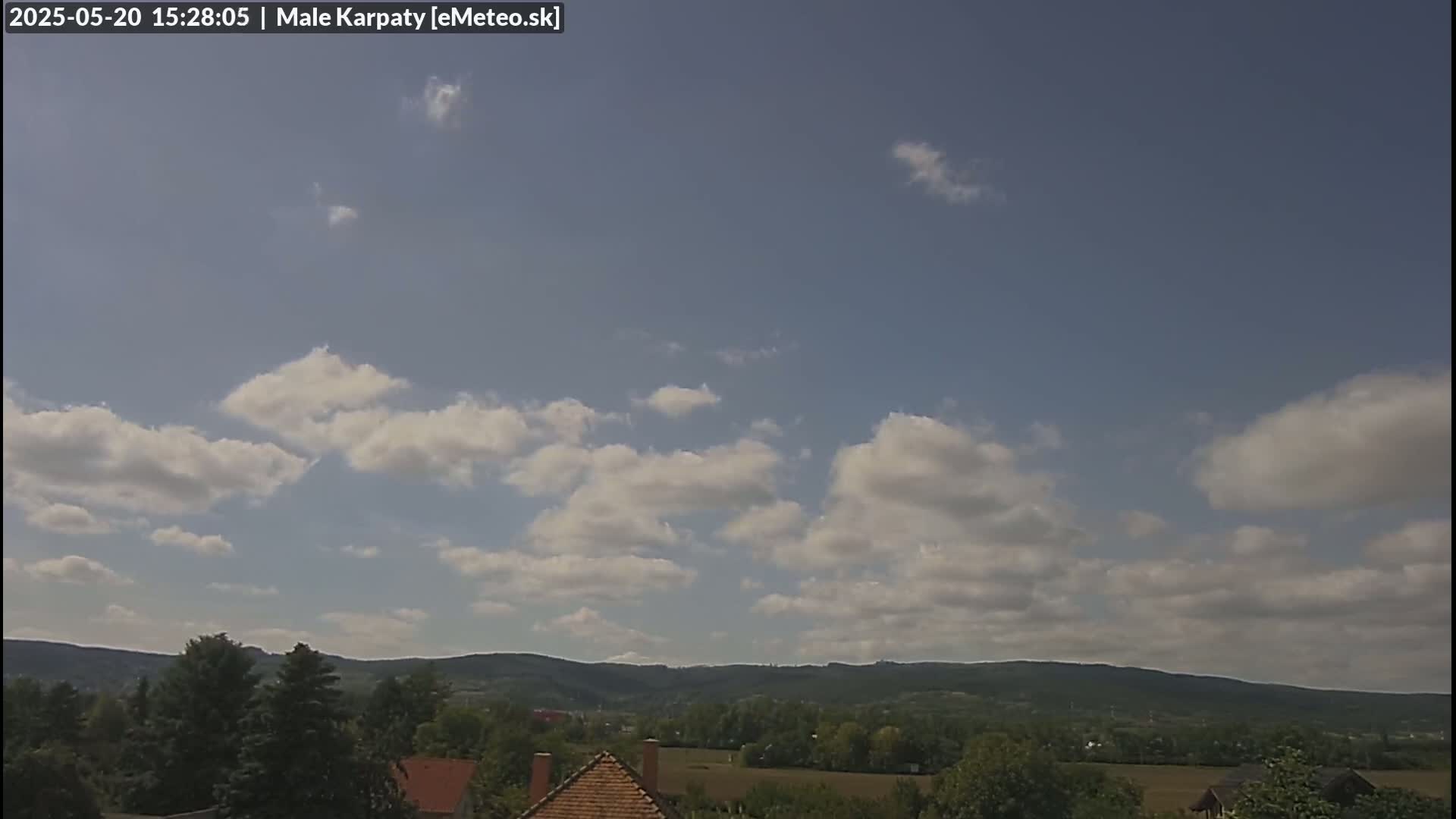 A partly cloudy sky overlooks a verdant valley and distant mountains.