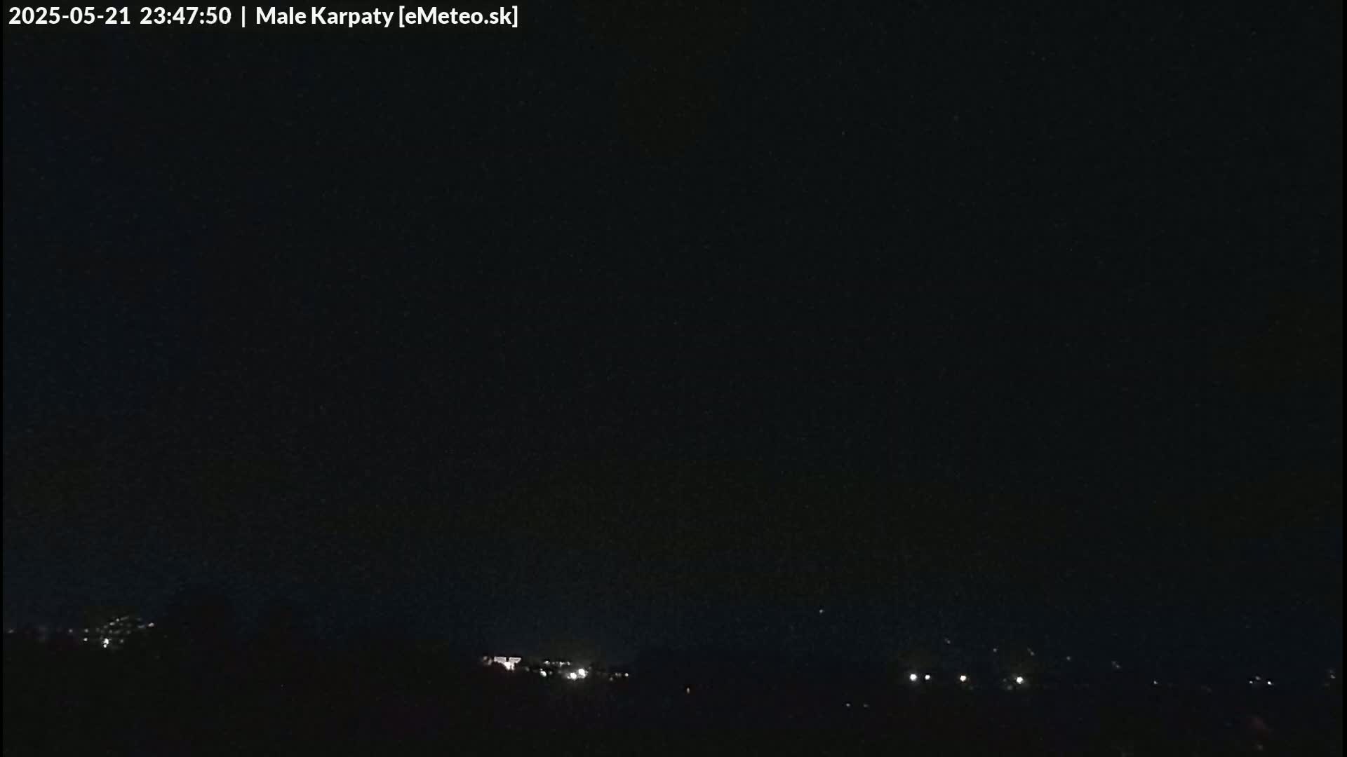 A nighttime view of a dark sky above a dimly lit landscape.