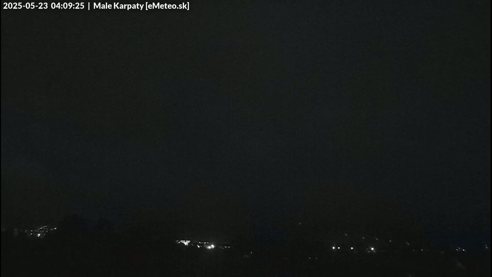 A nighttime long shot shows a dark, overcast sky over a dimly lit landscape with a few scattered lights.