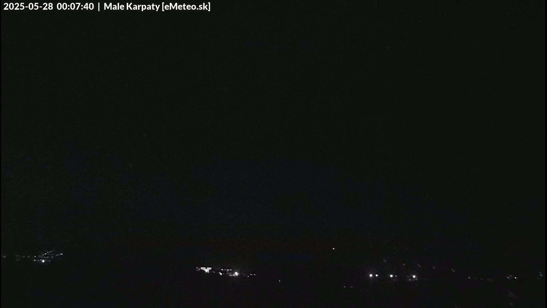 A nighttime long shot shows a dark sky over a low horizon line with faint lights visible in the distance.