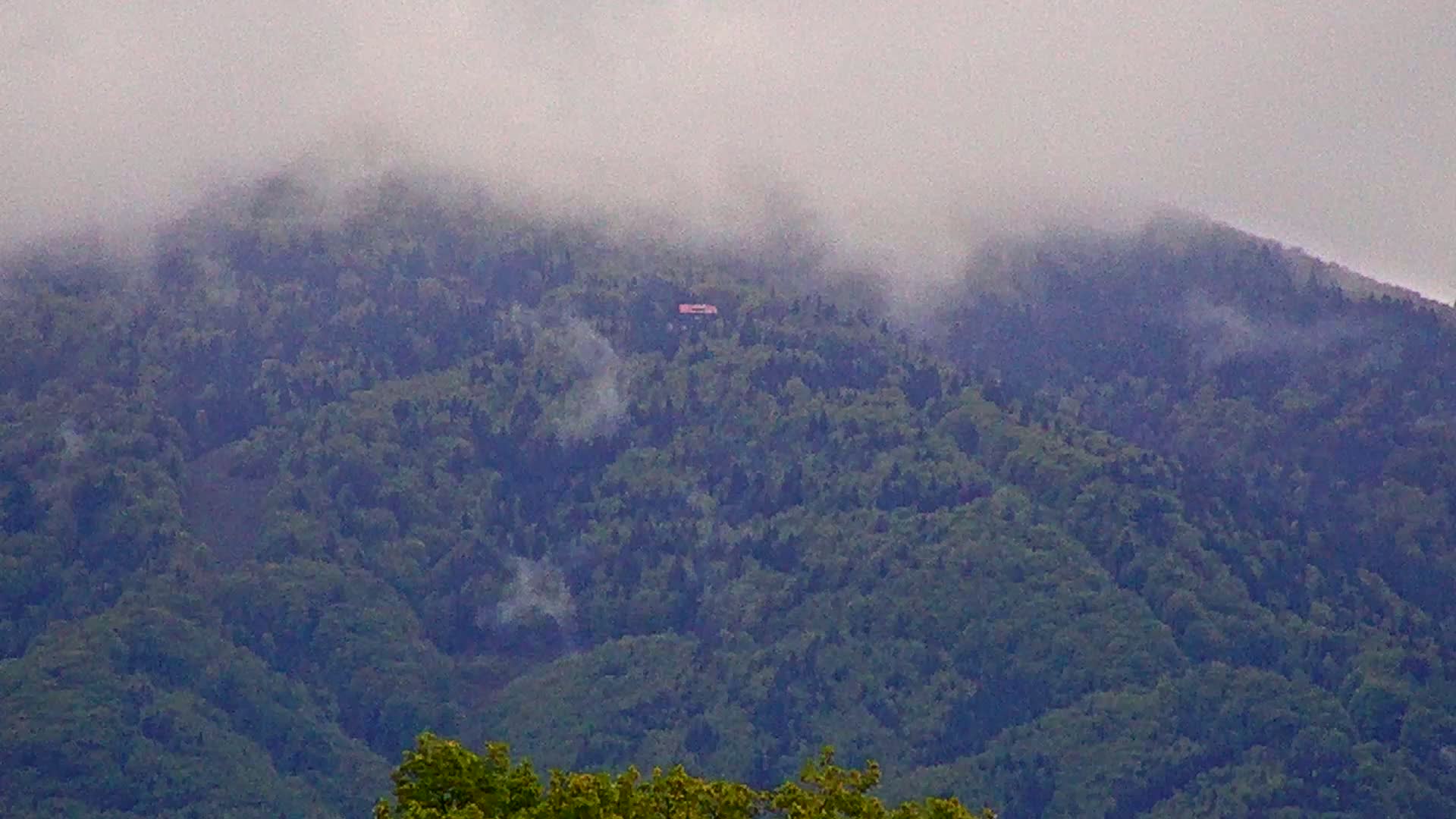 A misty, forested mountain is visible, with a small structure barely discernible in the mid-ground.