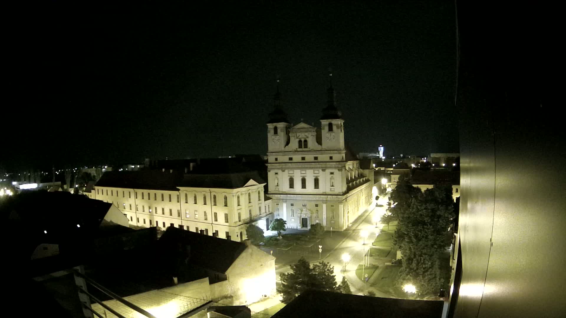 A large, illuminated cathedral and surrounding buildings are seen at night from an elevated vantage point.