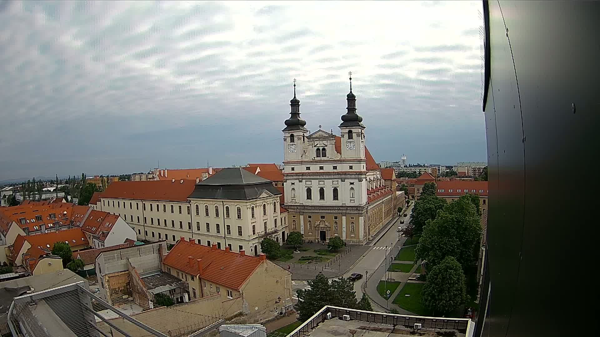 An elevated view of a city square with a large church at its center, under a cloudy sky.