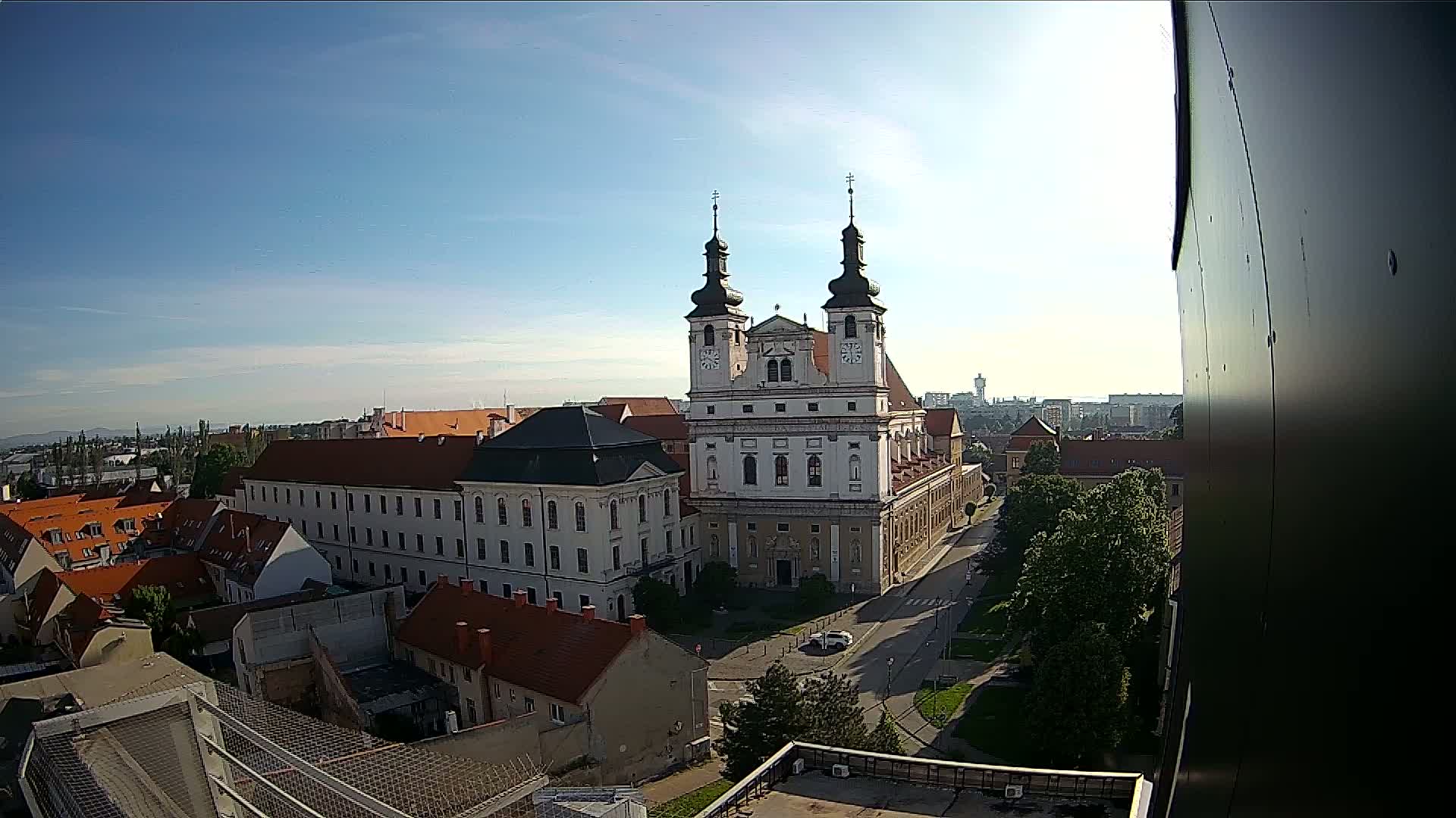 A large church with two towers stands in the center of a city on a sunny day.