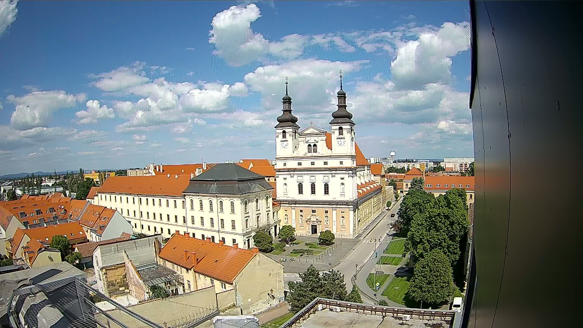A large church with two towers is situated in the center of a town under a partly cloudy sky.