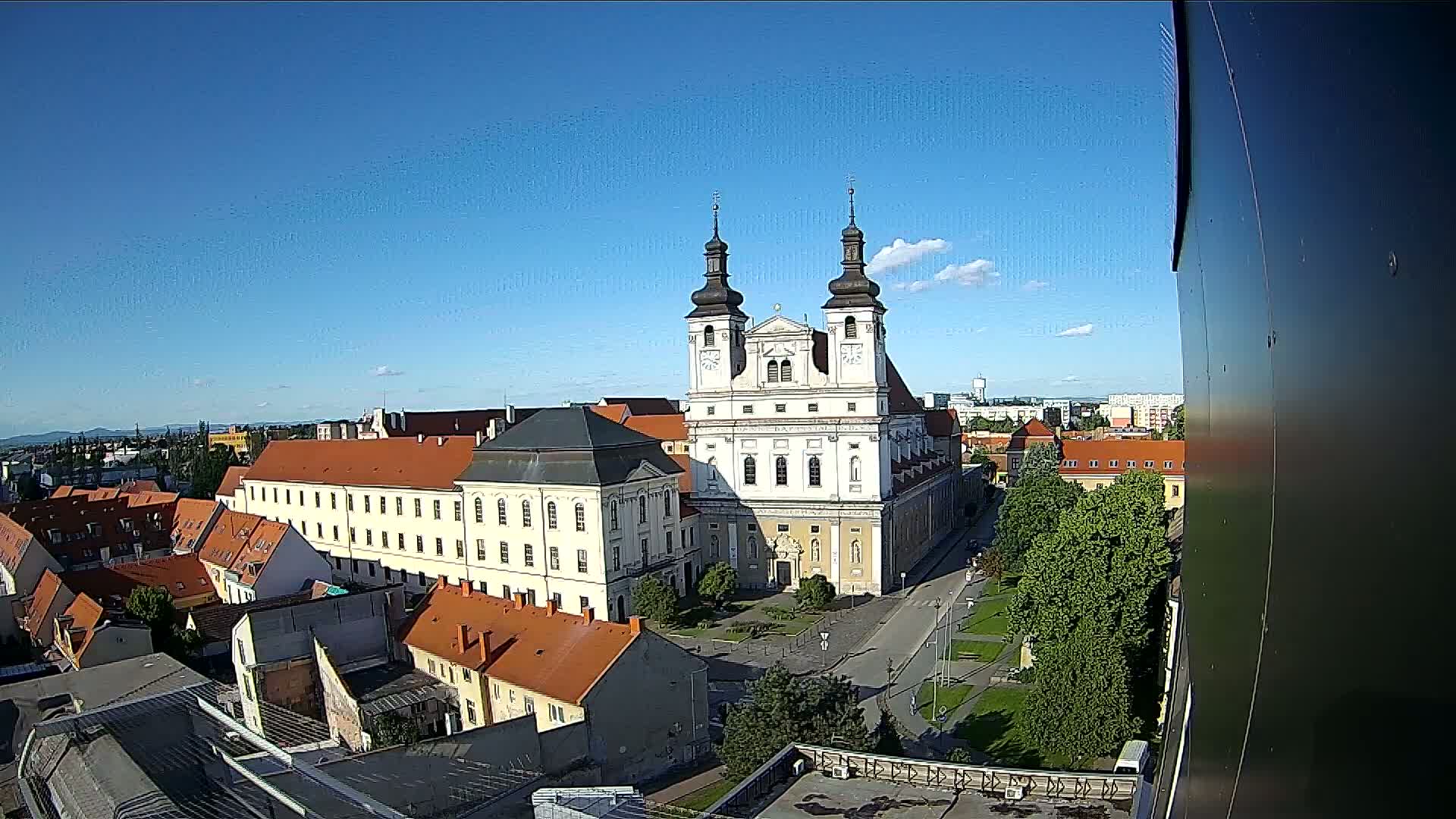 A large cathedral and surrounding buildings are seen from an elevated viewpoint on a clear, sunny day.