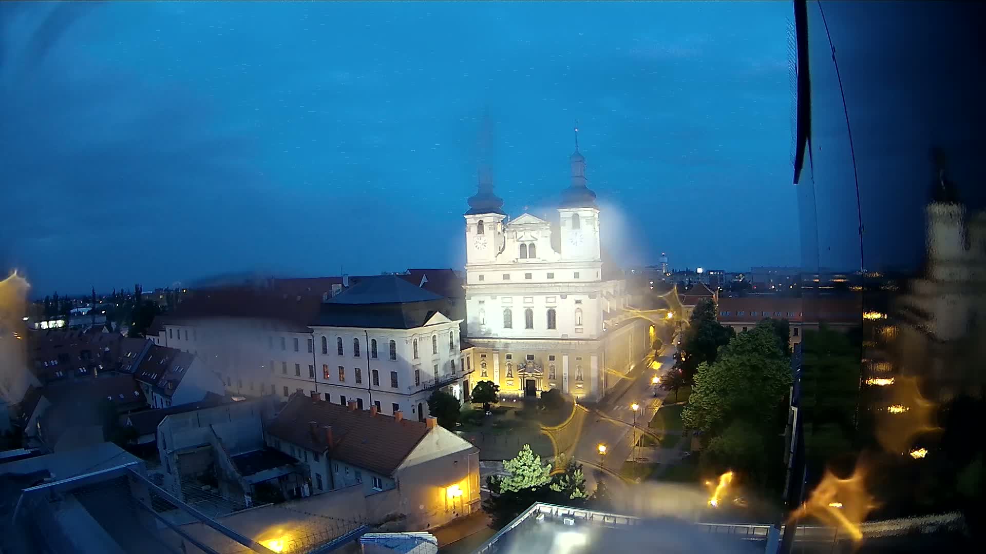 A brightly lit church and surrounding buildings are seen at night under a dark, clear sky.