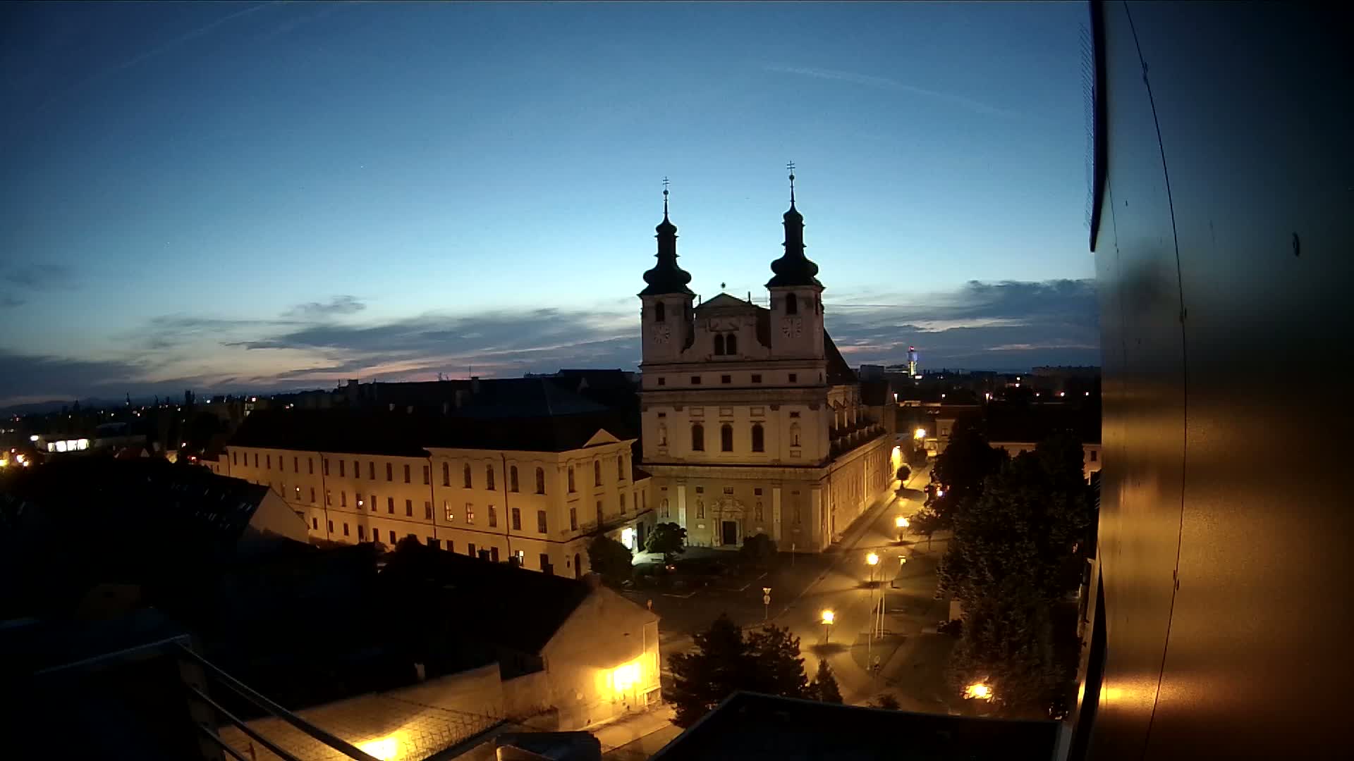 A large church stands in a city at twilight, under a mostly clear sky.