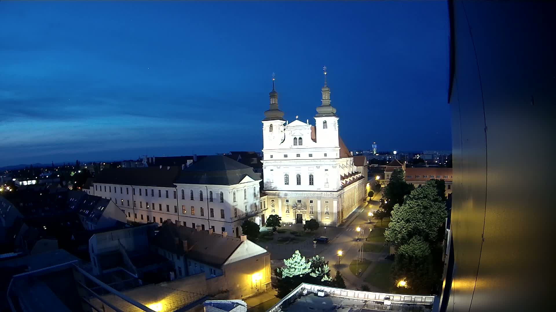 A brightly lit church stands in the center of a city at night under a clear, dark blue sky.