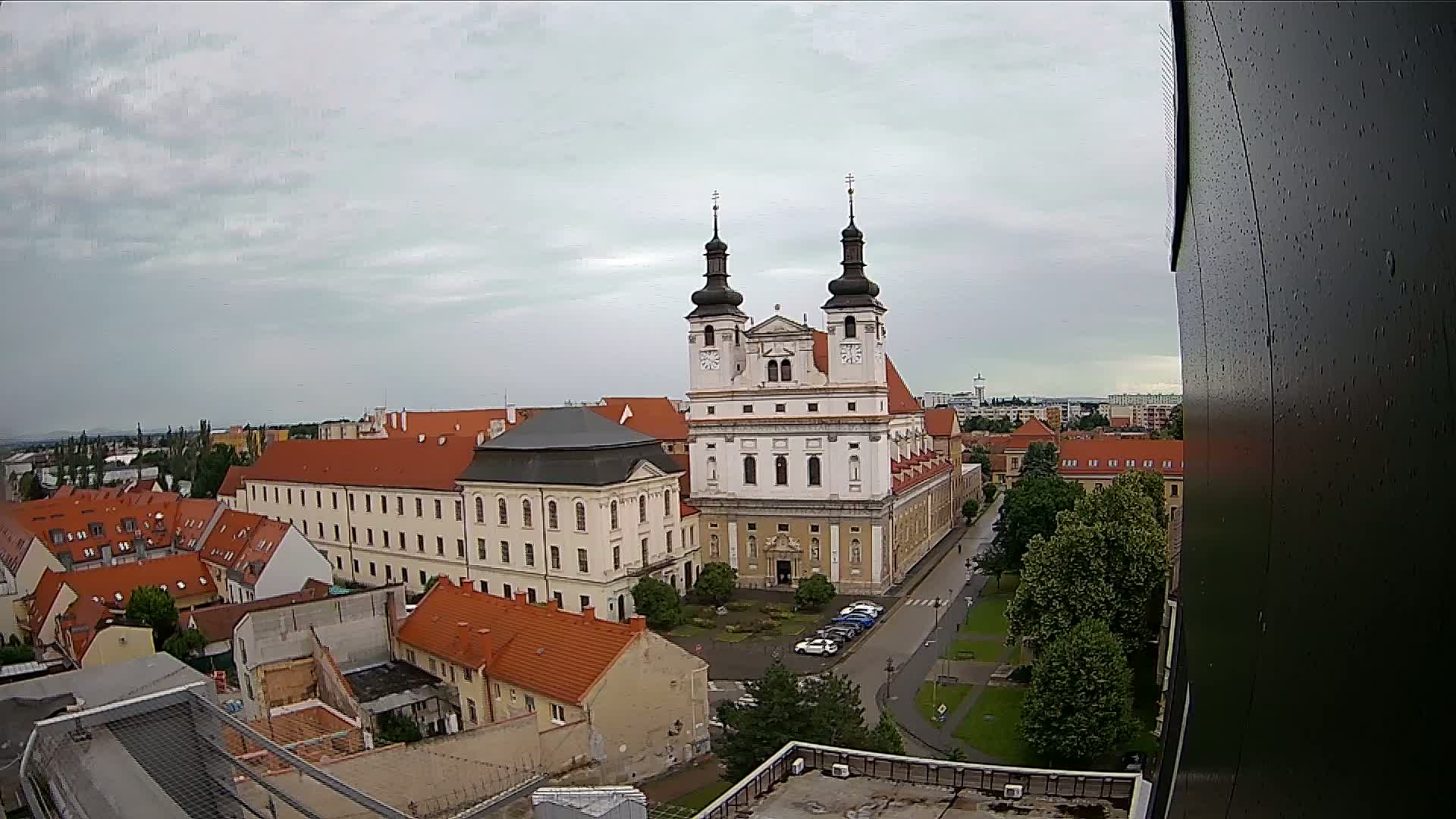 An elevated view shows a large church and surrounding buildings under a cloudy sky.