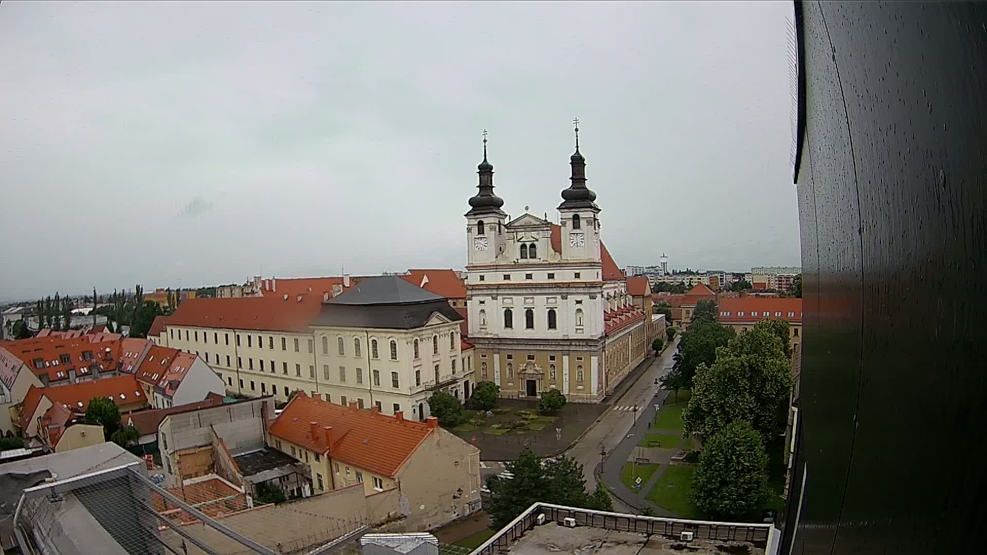 An elevated view of a city on an overcast day shows a large church complex surrounded by smaller buildings and green spaces.