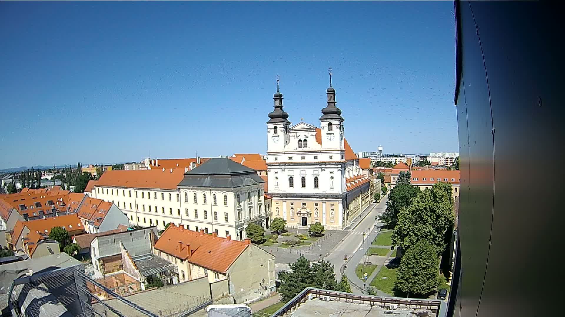 A high-angle view on a clear, sunny day shows a large church and surrounding buildings in a European city.