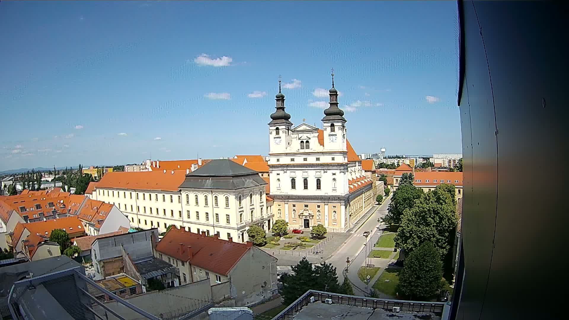 An elevated view of a large church complex with orange-roofed buildings surrounding it under a clear blue sky.