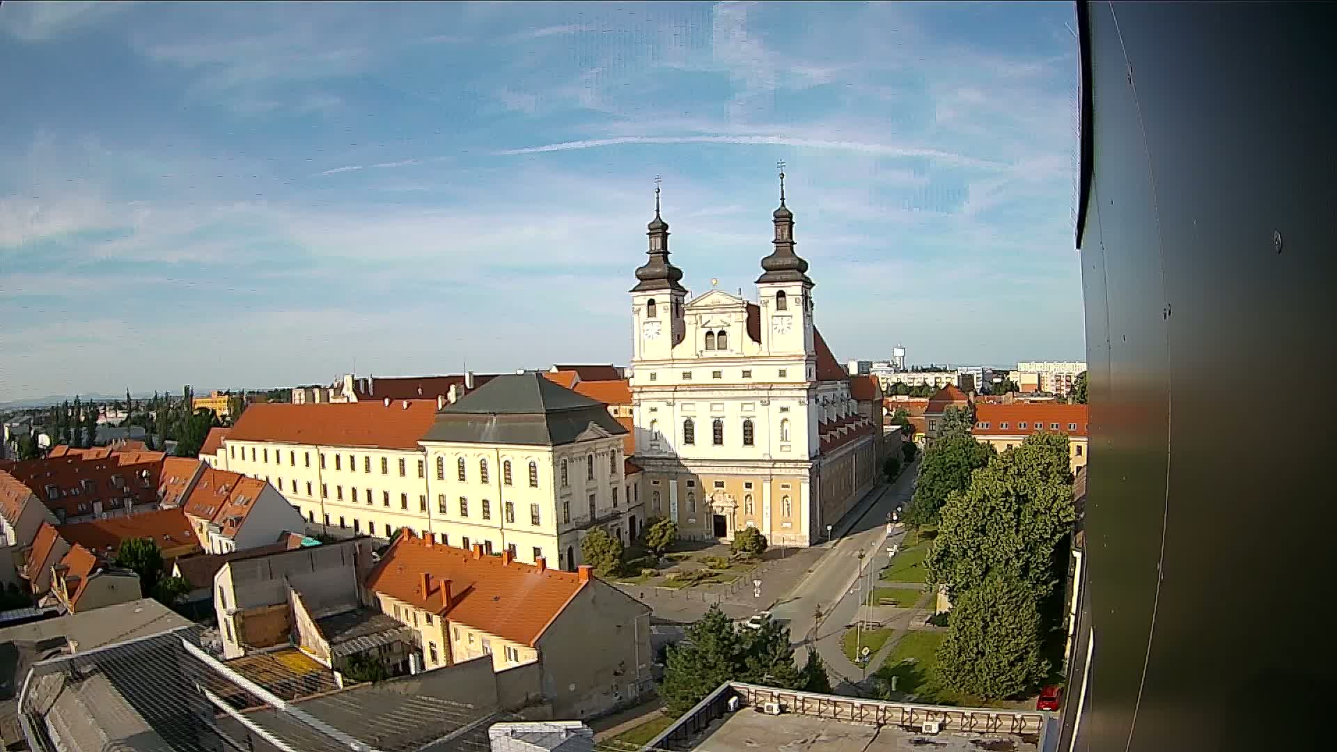 An elevated view on a sunny day shows a large church complex surrounded by smaller buildings and green spaces.