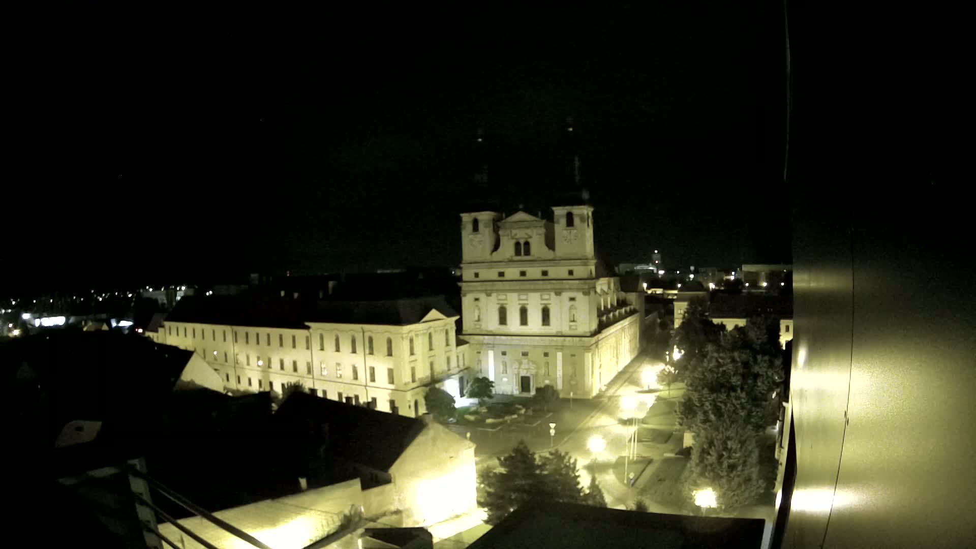A large, illuminated church and surrounding buildings are visible at night.
