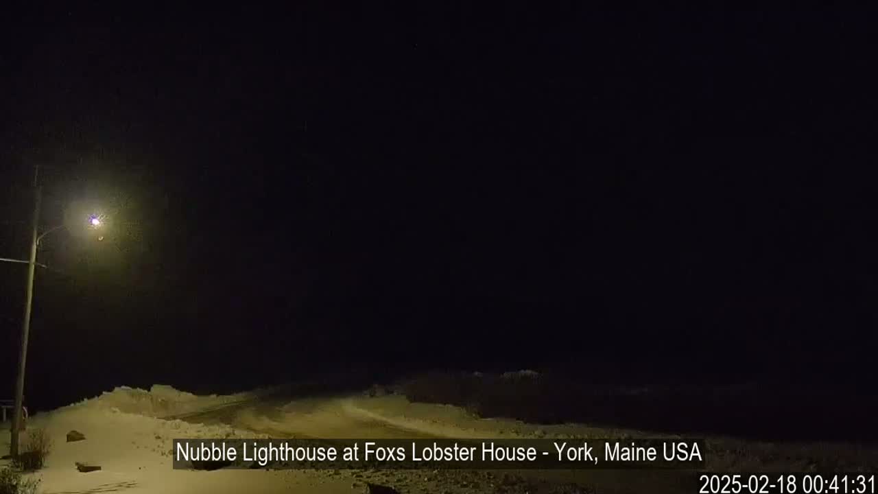 A snow-covered landscape is visible at night under a dark sky, illuminated by a single streetlight.