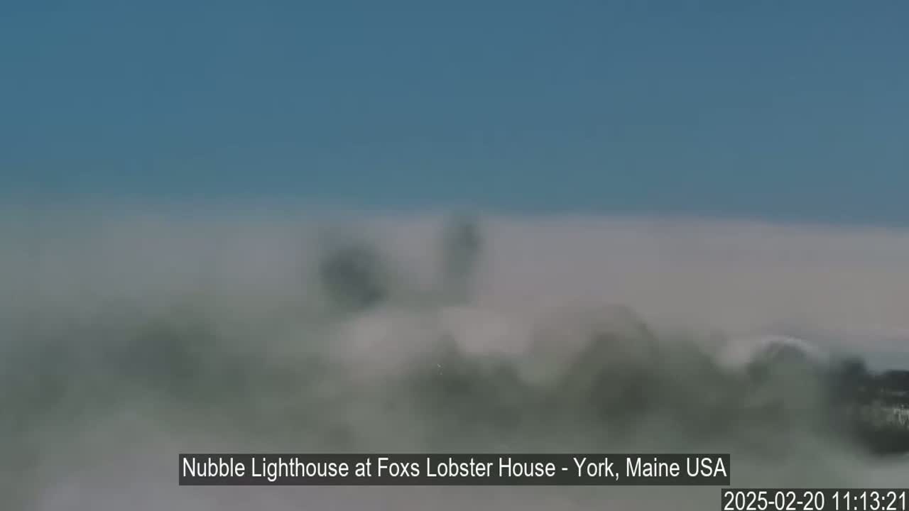 A partially obscured lighthouse is seen through a thick fog.