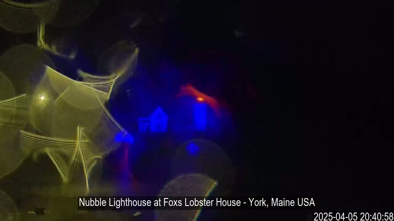 A blurred image shows a lighthouse at night, with bright yellow and blue light streaks obscuring the view.