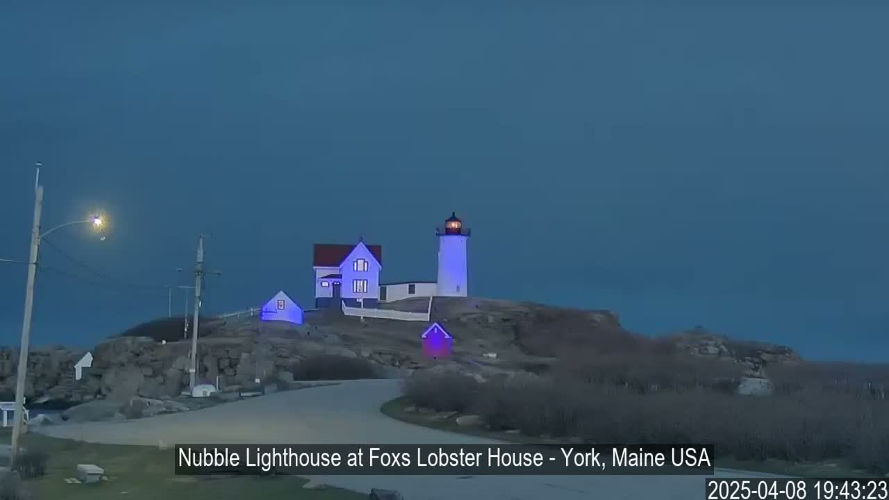 A lighthouse and keeper's house sit atop a rocky outcrop under a twilight sky.