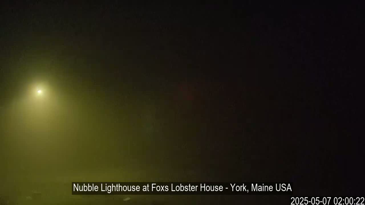 A bright light shines through heavy fog at night.