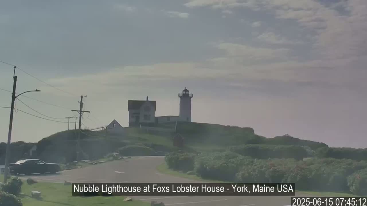 A lighthouse and adjacent buildings sit atop a hill on a hazy day.