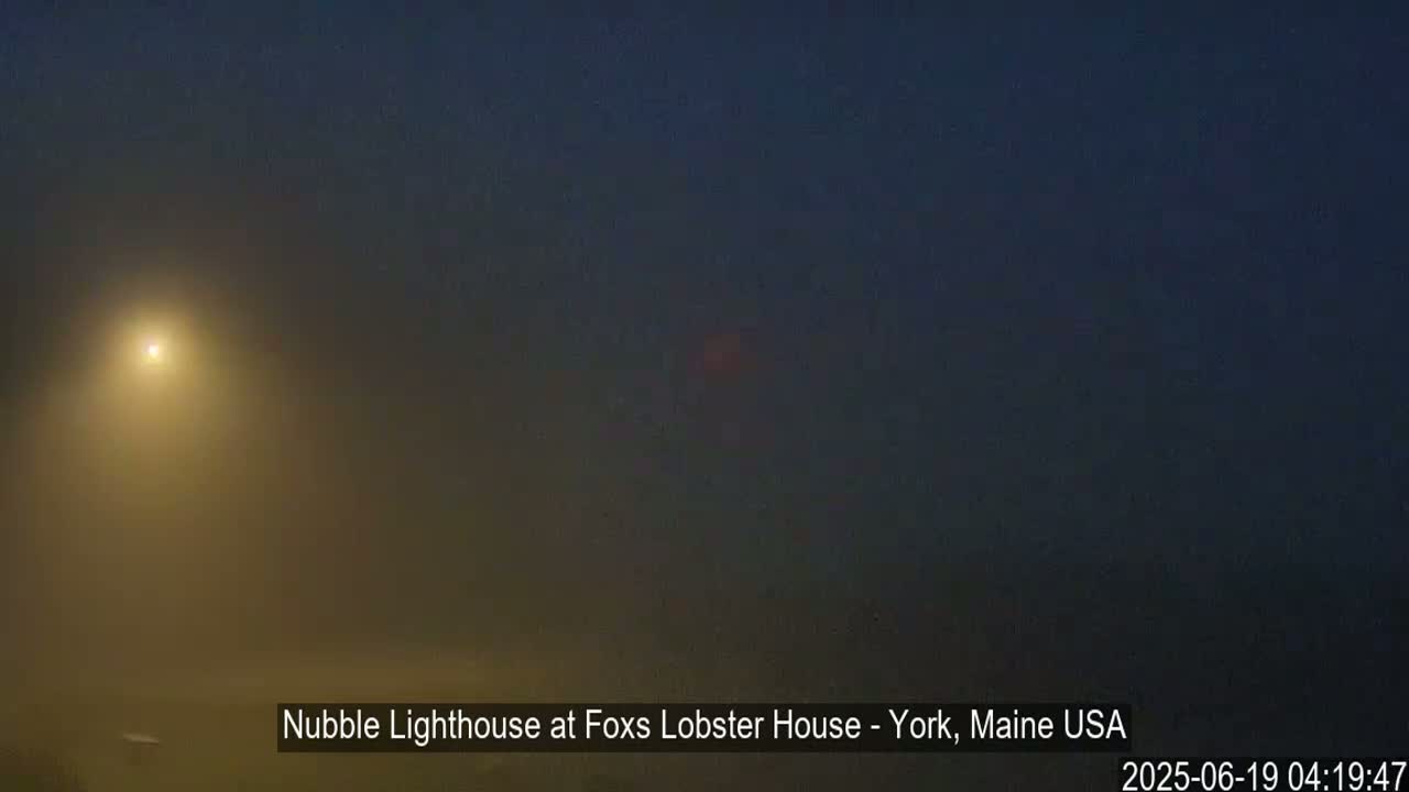 A hazy, dark scene is illuminated by a single bright light in the fog.