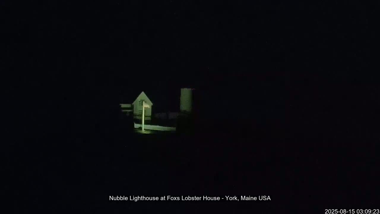 A dimly lit house and a taller structure are visible at night.
