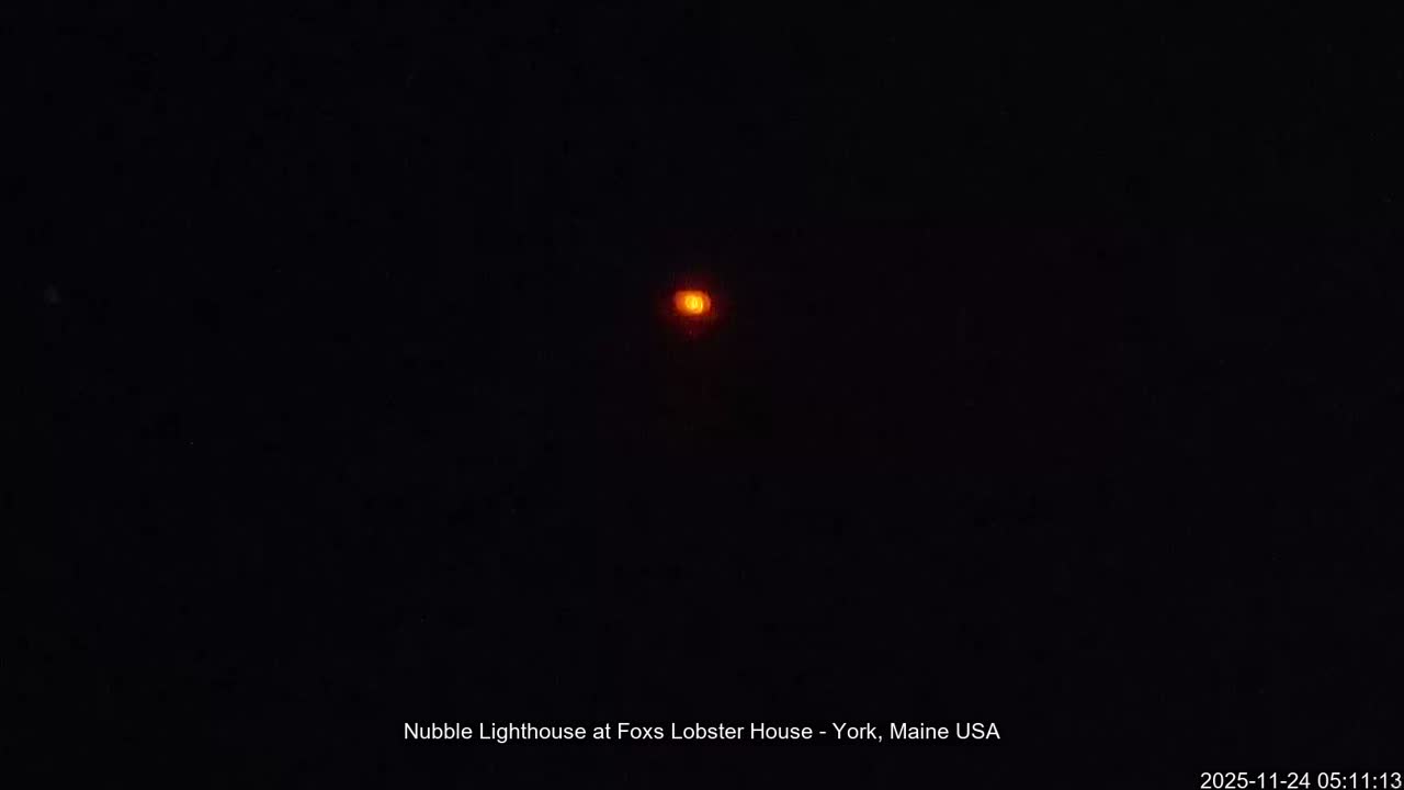 A small, blurry orange light is the sole visible element in an otherwise pitch-black image, suggesting a clear night.