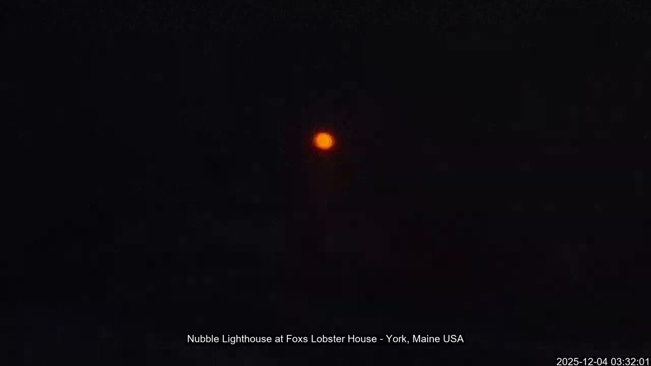 A single, blurry orange light glows against a vast, clear, dark night sky.