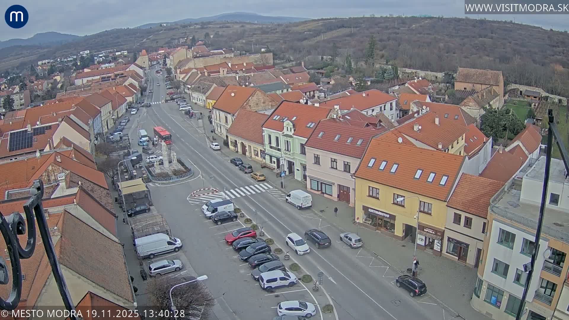 A nighttime, high-angle view of a town's street and buildings with cars parked along the sides.