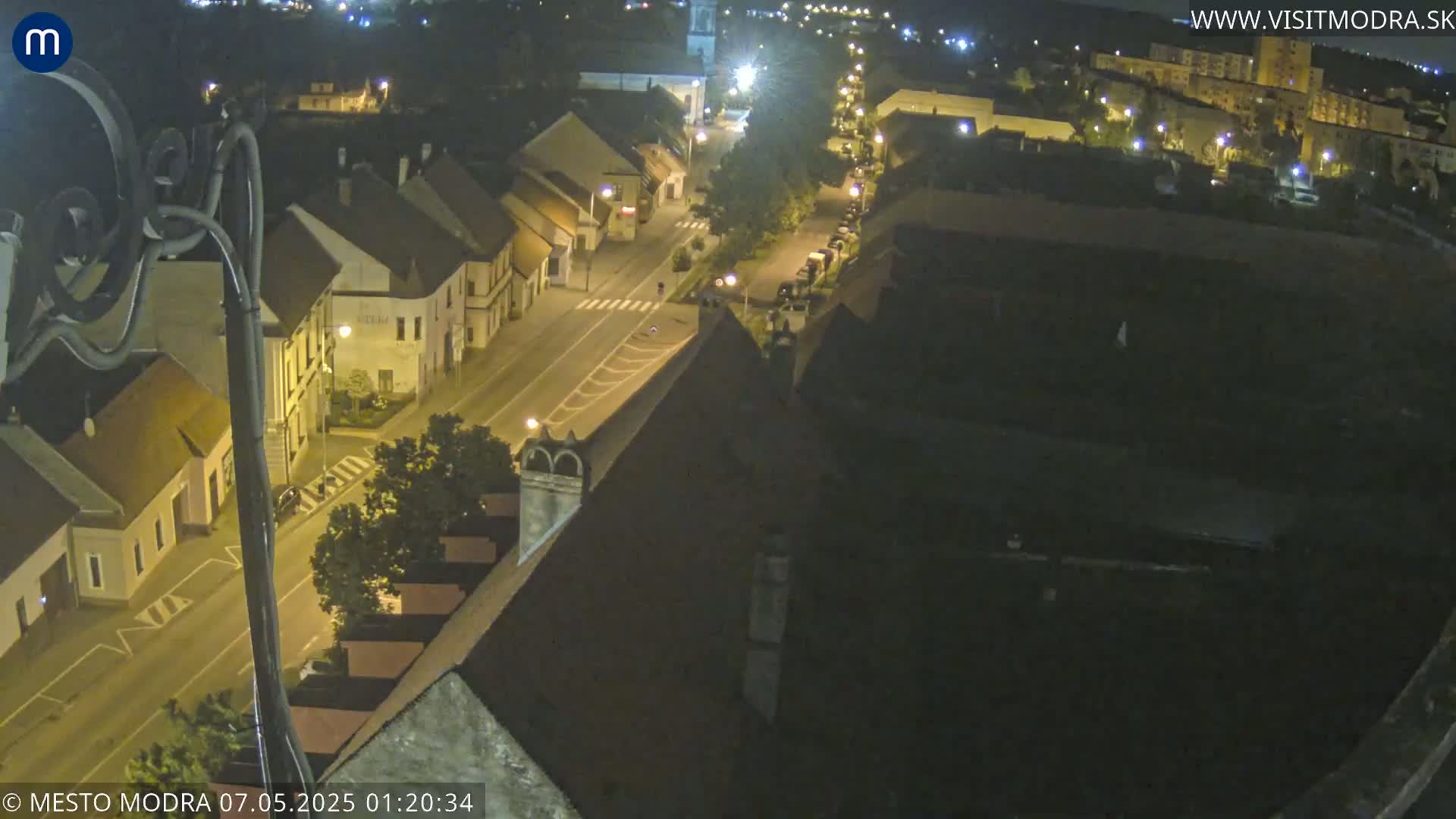 A nighttime, high-angle view of a town's streets and buildings illuminated by streetlights.
