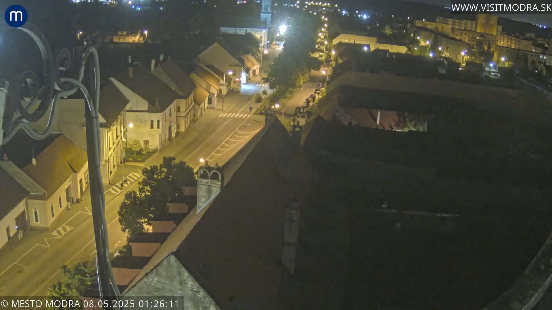 A nighttime, high-angle view shows a town's streets and buildings illuminated by streetlights.
