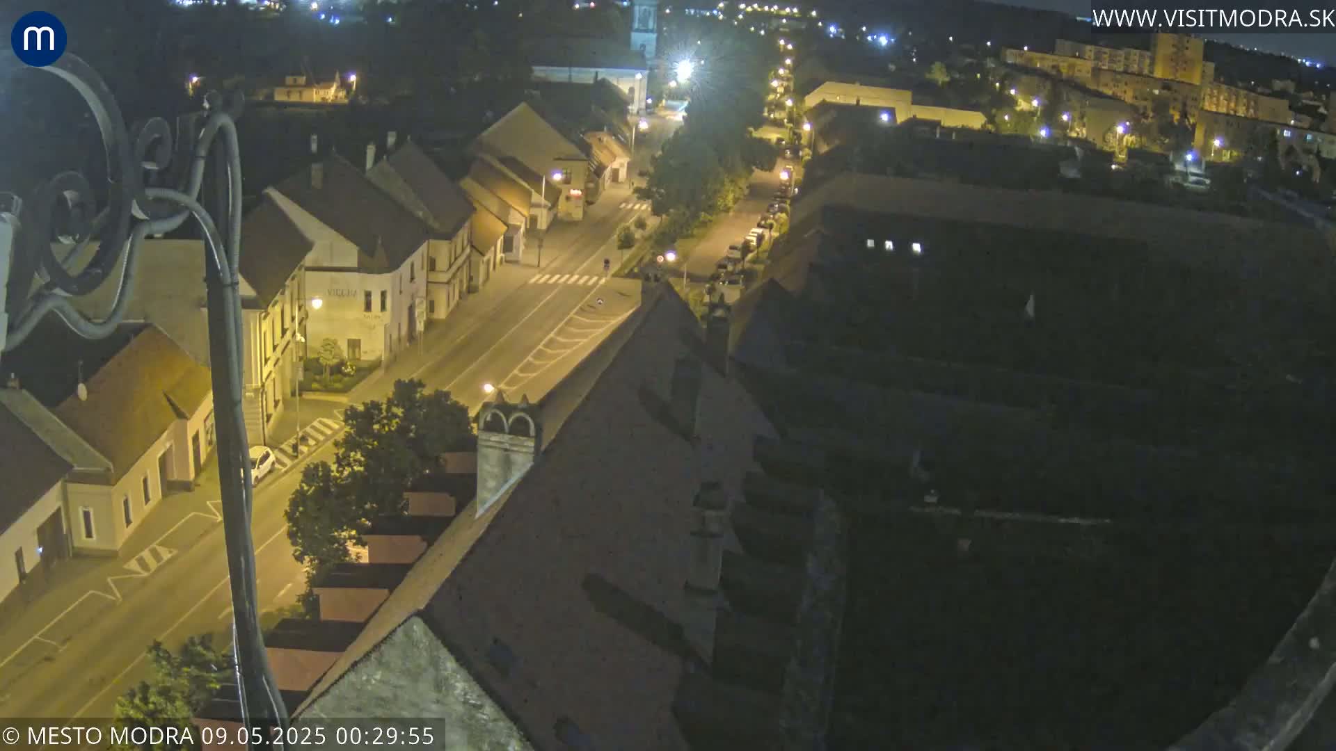 A nighttime aerial view of a town's streets and buildings, illuminated by streetlights.