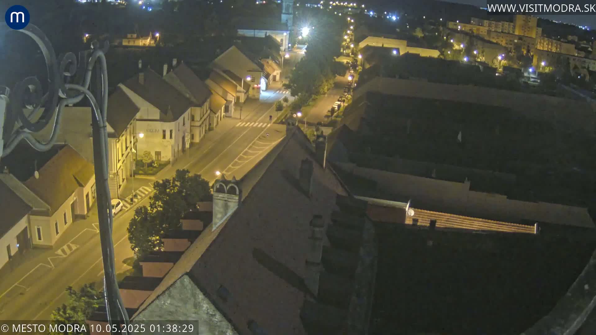 An elevated nighttime view of a town's streets and buildings, illuminated by streetlights.