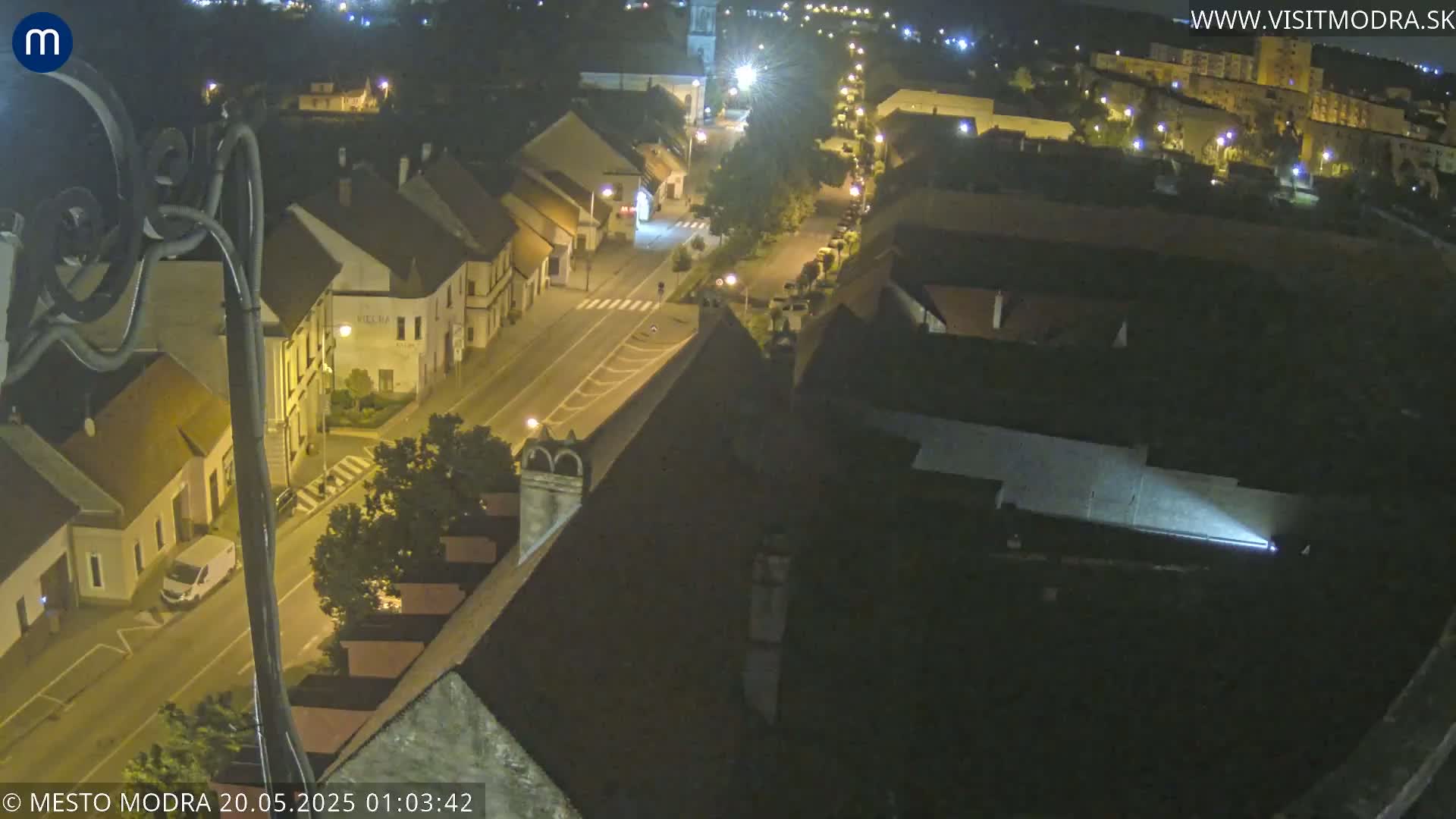 A nighttime, high-angle view shows a town's street and buildings illuminated by streetlights.