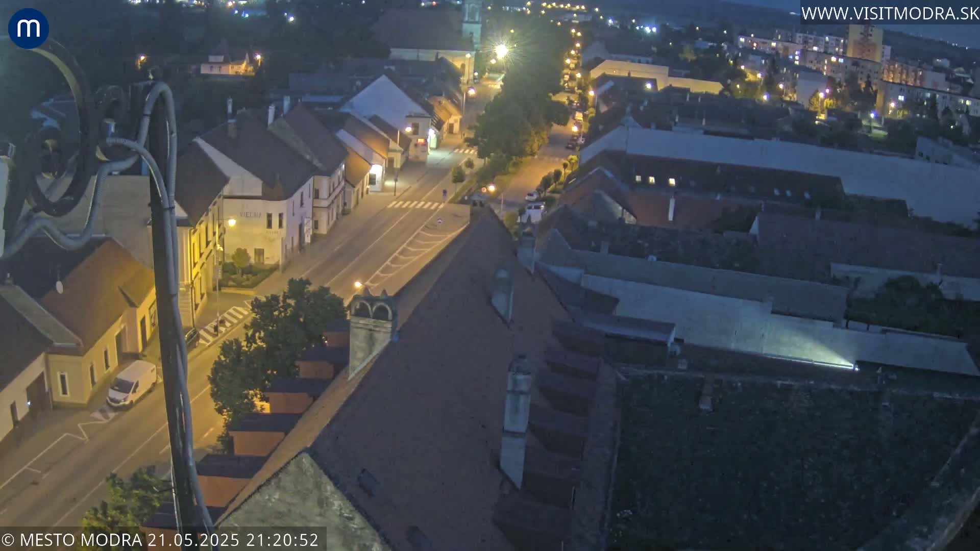 An aerial nighttime view shows a town with streetlights illuminating the streets and buildings.