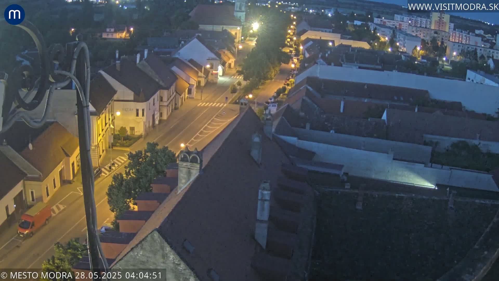 A nighttime, high-angle view shows a town's streets and buildings illuminated by streetlights.