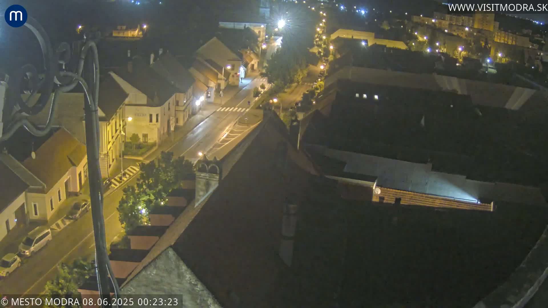 A nighttime aerial view of a town's streets and buildings, illuminated by streetlights.