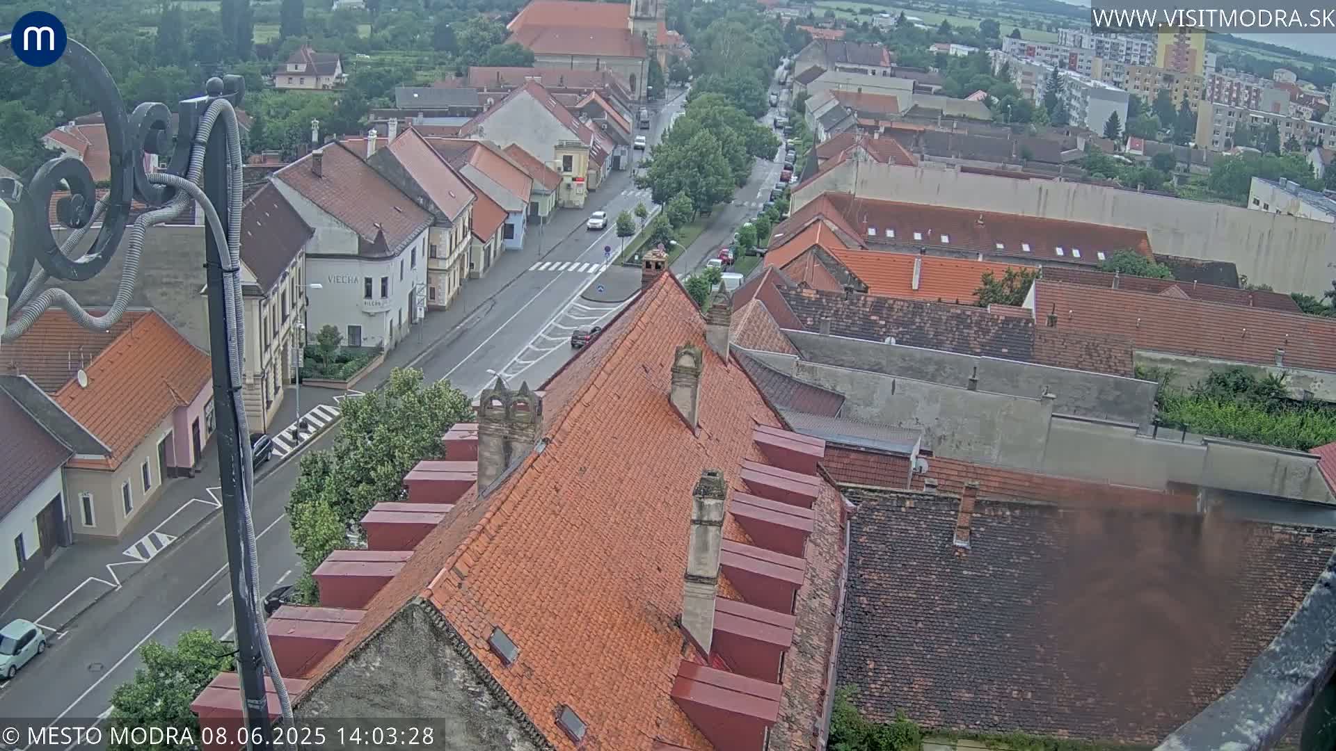 A high-angle view of a town's streets and rooftops on an overcast day, showing a mix of buildings and a road with some traffic.