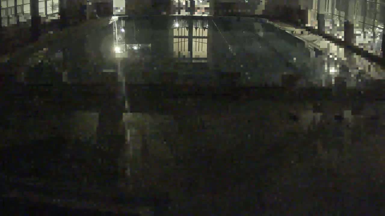 A dark, nighttime view of a reflecting pool showing the reflection of a gated structure.