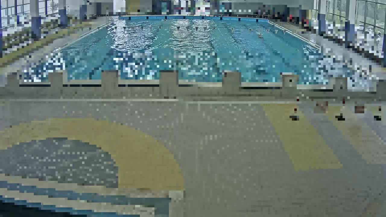 An indoor swimming pool with several people swimming in it.