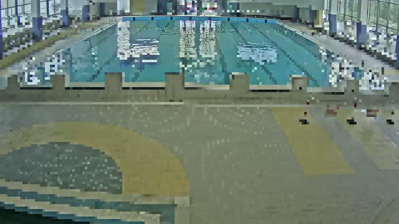 An indoor swimming pool with several lanes is seen from above, the surrounding area is mostly empty.