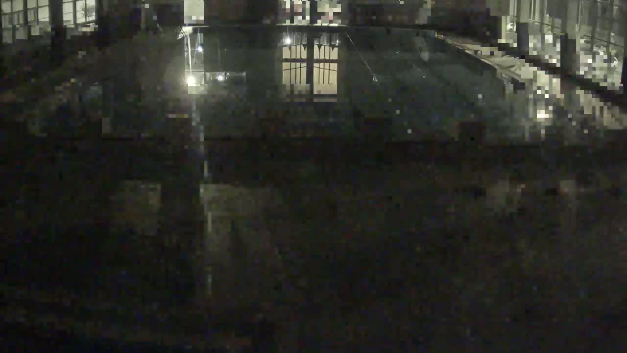 An indoor swimming pool is visible at night, its surface reflecting light.