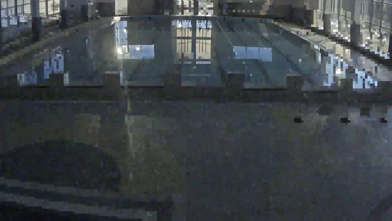 A dark, reflective surface shows the blurry reflection of a building's interior at night.