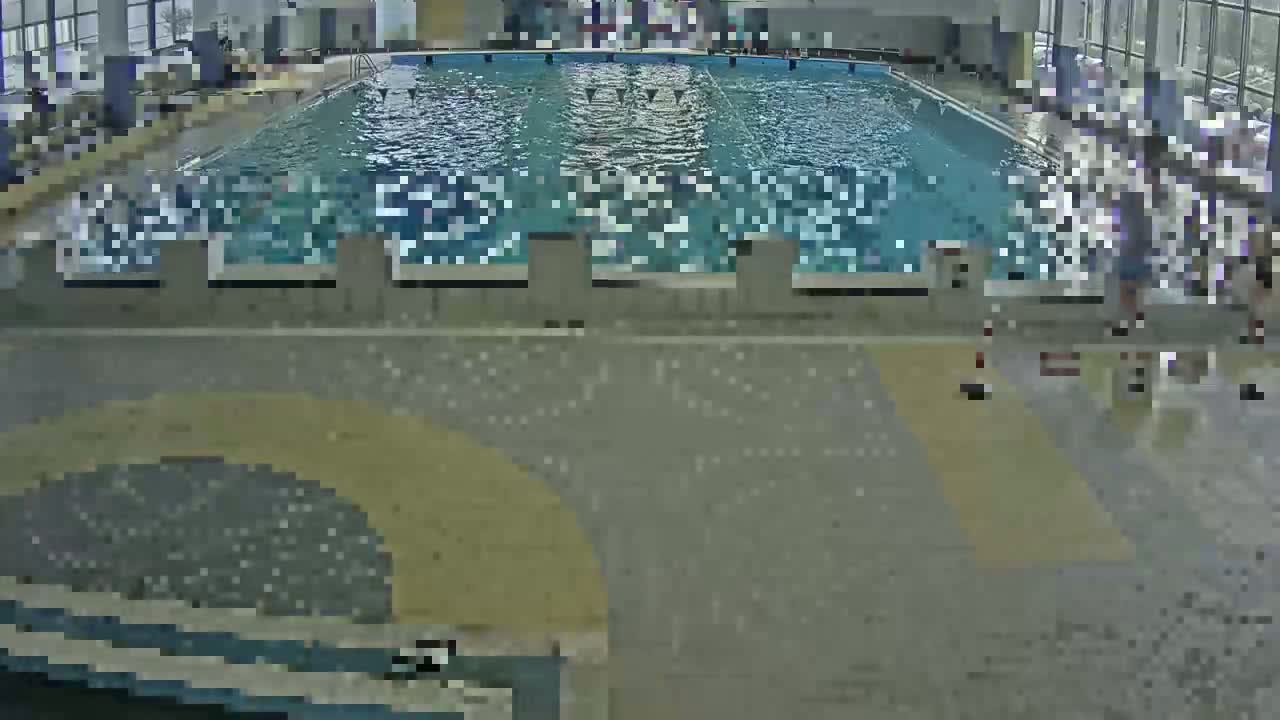 An indoor swimming pool with people around it and a wet floor.