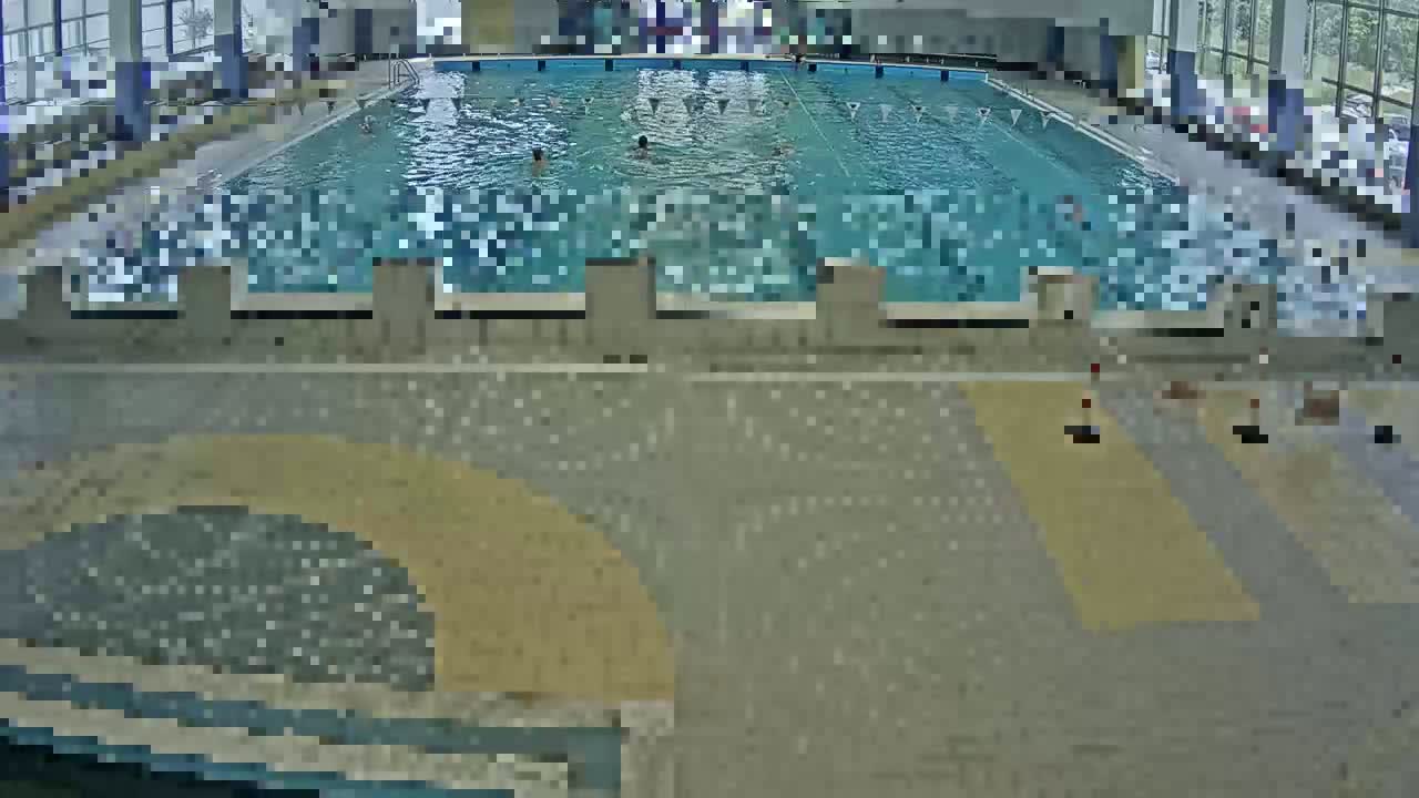 An indoor swimming pool with several people swimming in it.