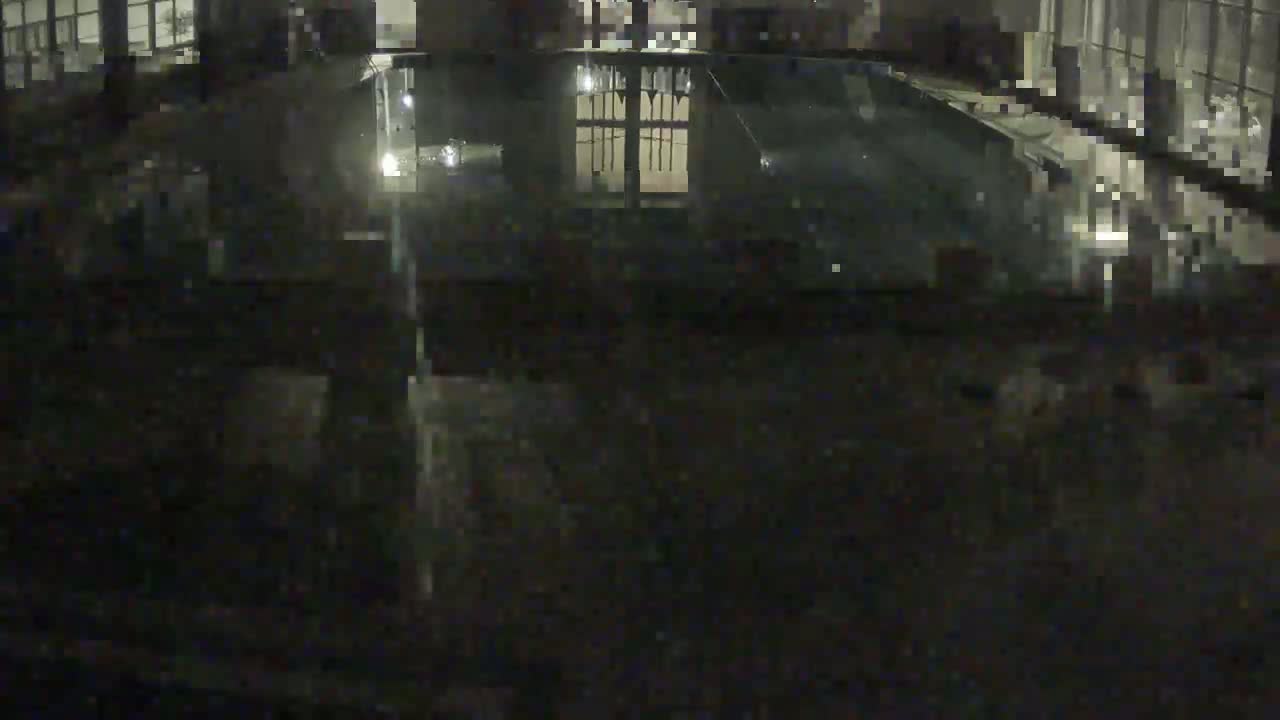 A dark, nighttime view of a reflective, possibly glass-covered, area overlooking an interior space with a gated door.