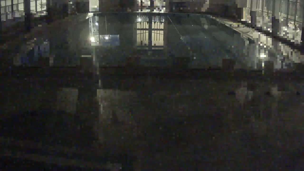 A dark, indoor view of a still body of water reflecting a window at night.