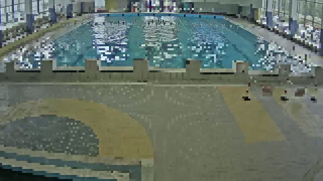 An indoor swimming pool with several people swimming in it.